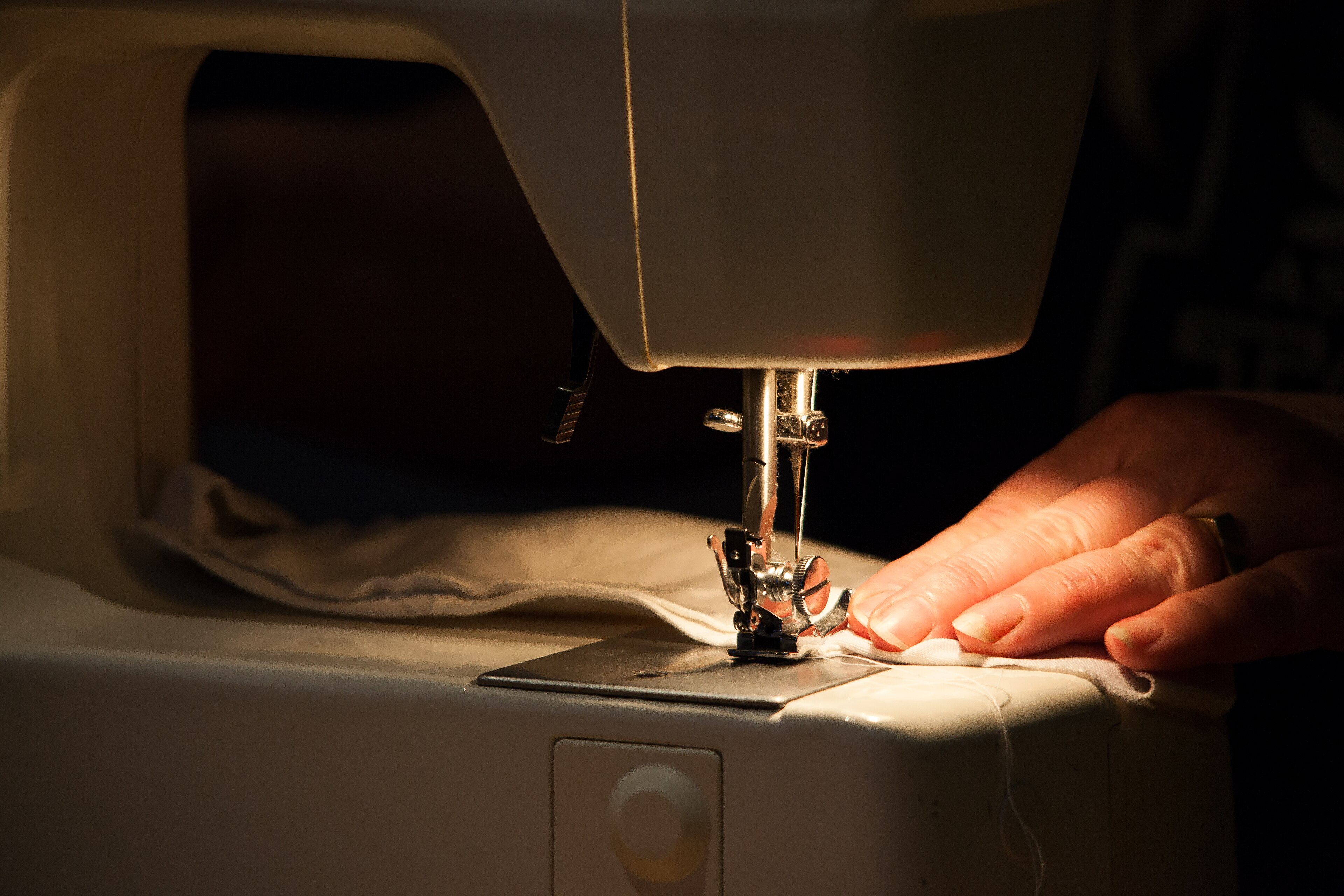 Handen aan de naaimachine in het atelier